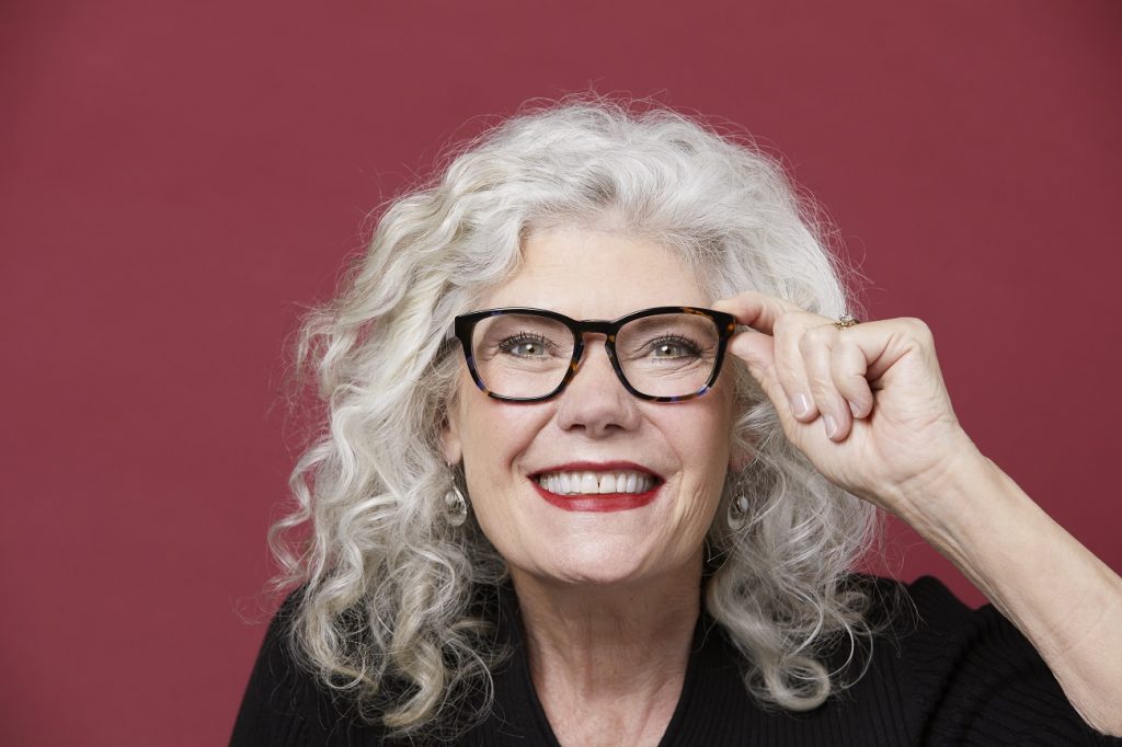 Woman with gray hair wearing glasses and smiling
